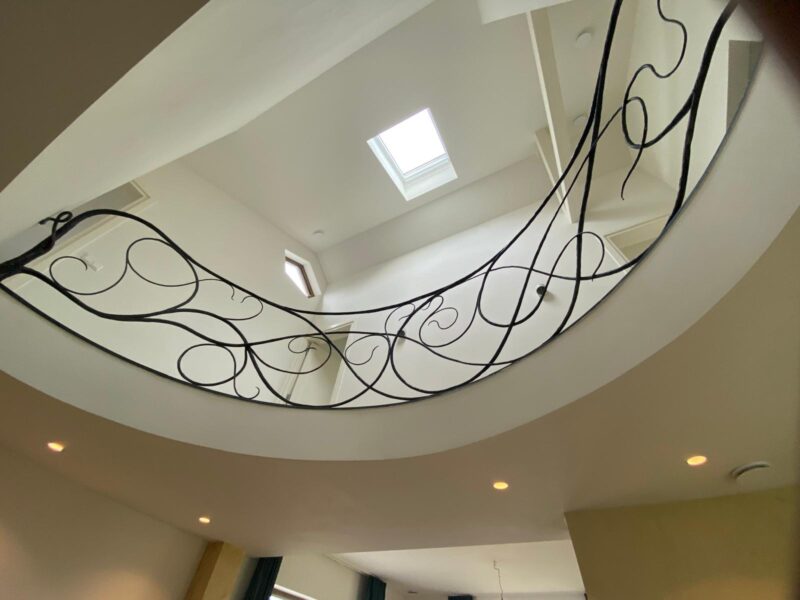 Vide met smeedijzeren balustrade en daglicht in duurzame verbouwing van jaren 60 woning