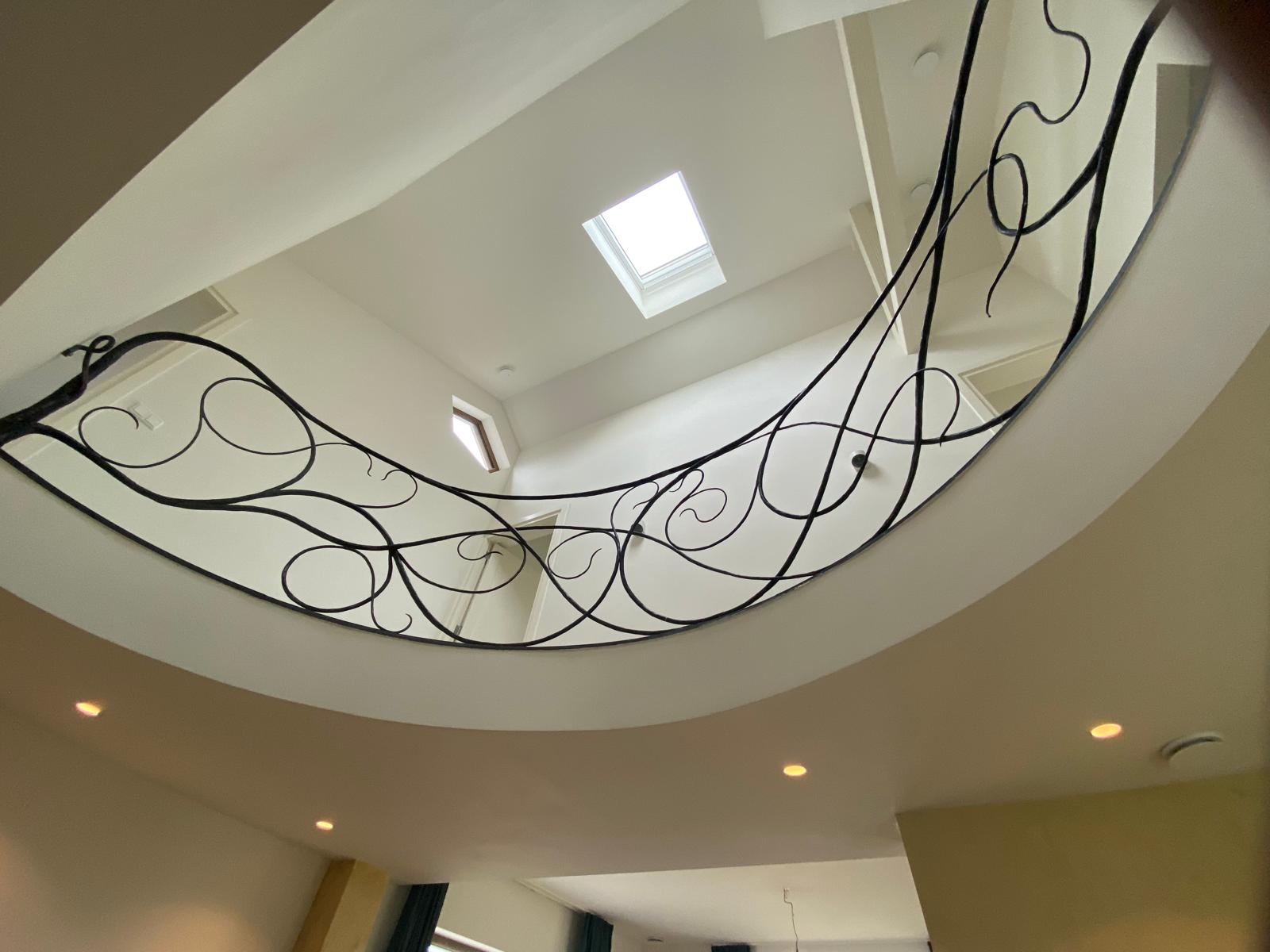 Vide met smeedijzeren balustrade en daglicht in duurzame verbouwing van jaren 60 woning