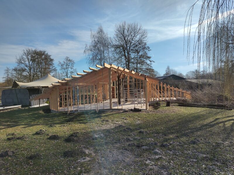 Organische dakconstructie van het ontvangstgebouw op Landgoed Energy Up met ritmische houten spanten in tegenlicht