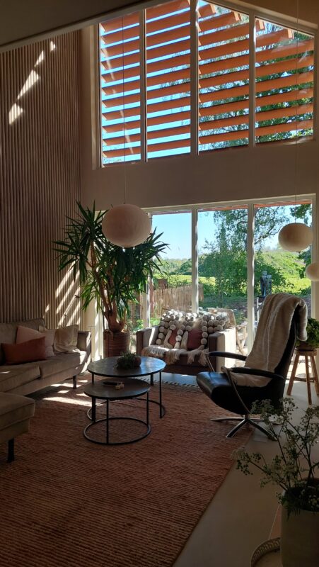 Lichte woonkamer met groot raam en uitzicht op groen landschap in ecologische woning in De Glind