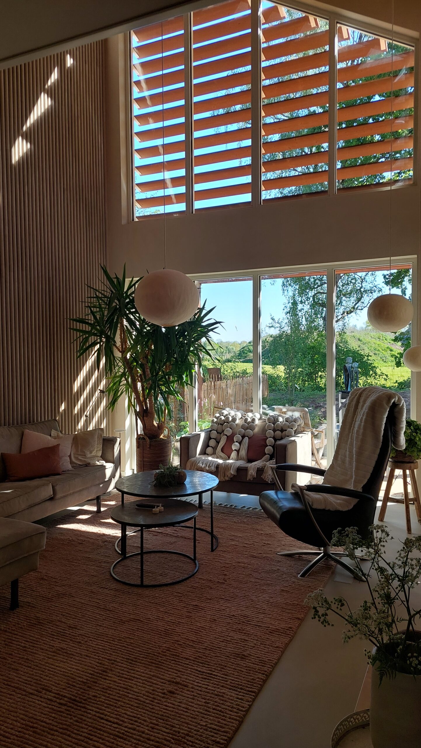 Lichte woonkamer met groot raam en uitzicht op groen landschap in ecologische woning in De Glind