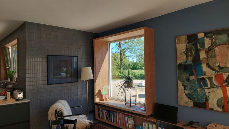 Houten raamdetail met diepe negge en uitzicht op natuur vanuit ecologische woning